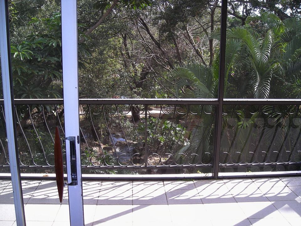 SCREENED IN PATIO WITH VIEW OF A GARDEN AND WATERFALLS.
