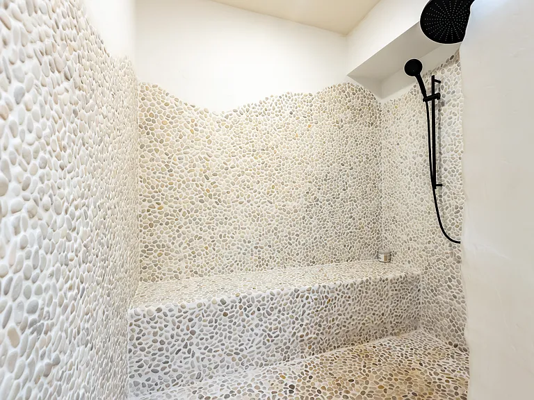 Primary bathroom shower. Beautiful rock pebbles