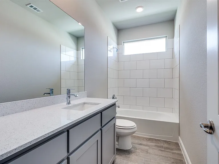 Full bathroom featuring tiled shower / bath combo, vanity, toilet, and hardwood / wood-style flooring