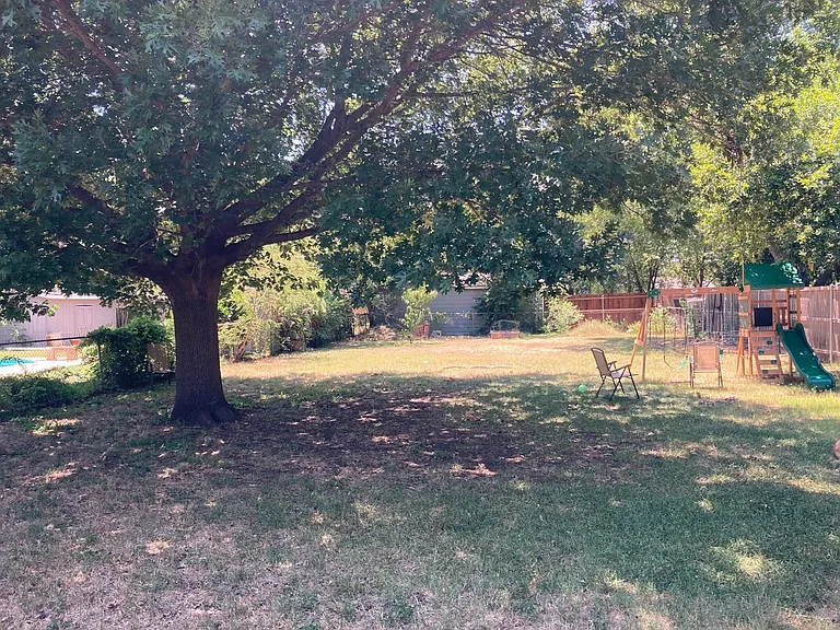 Large backyard with a beautiful oak tree providing the perfect Summer shade (play structure not included)