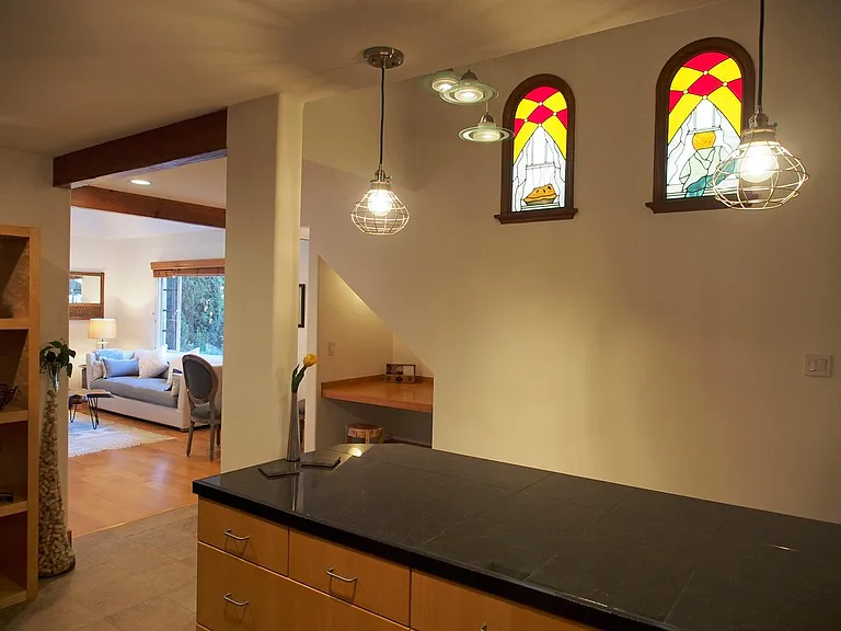View from kitchen corner out toward desk nook and living room. Open floor plan. Original custom stain glass windows.