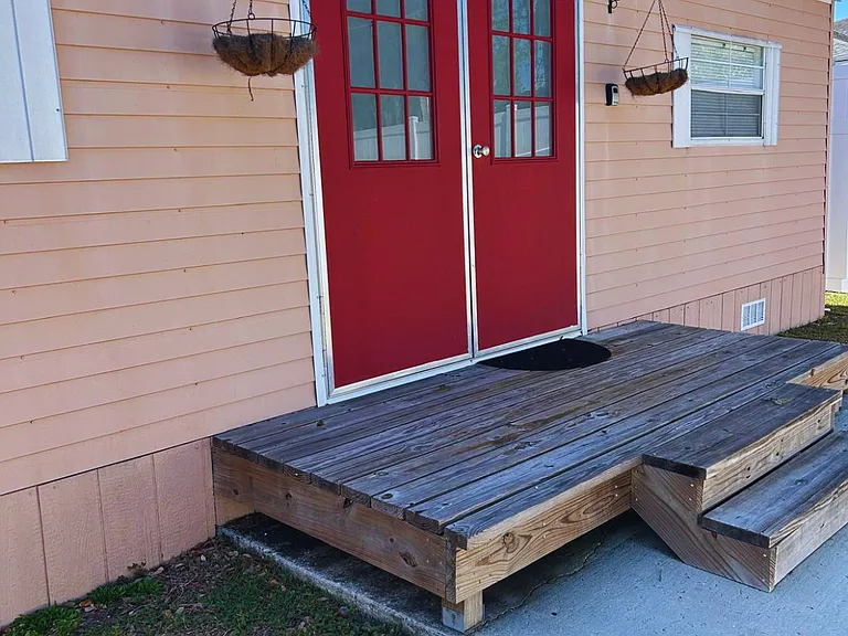 The main entrance features a red door with white decorative details and two steps.