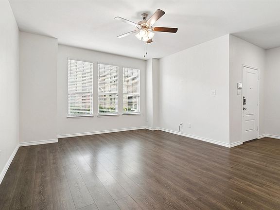 Living room with large windows letting in natural light and ceiling fan