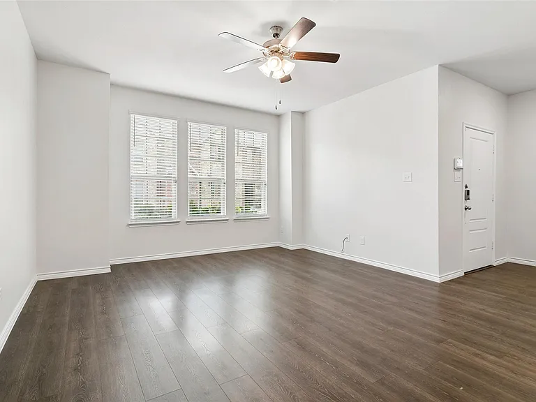 Living room with large windows letting in natural light and ceiling fan