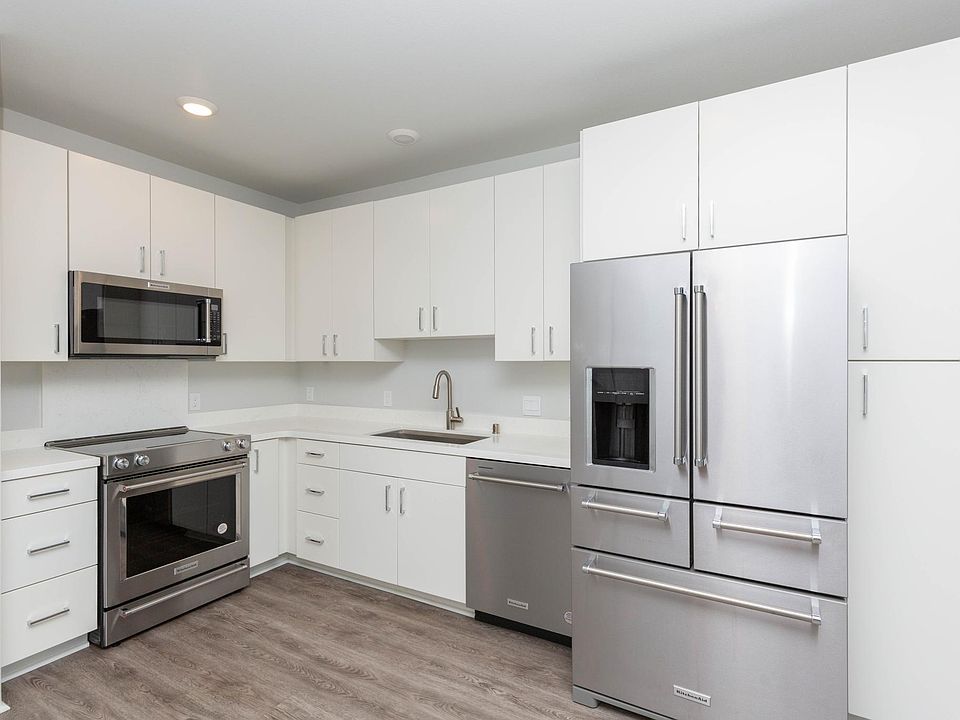 Modern kitchen with stainless steel appliances, LVP flooring, and quartz countertops.