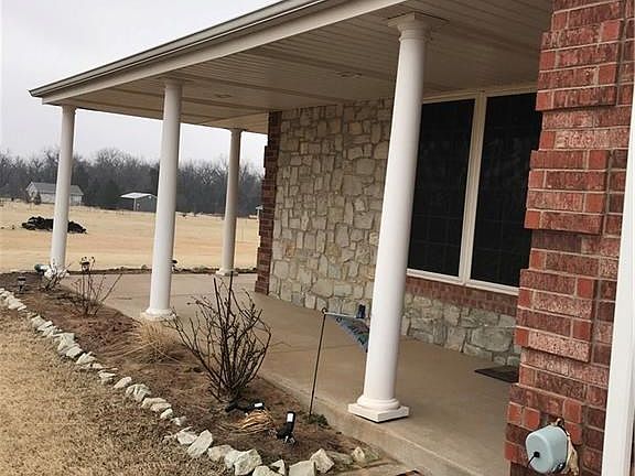 White Pillars Set Off The Wrap-Around Porch with Stone.