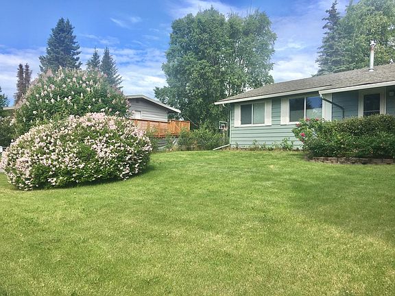 Large front yard with lilac and rose bushes.