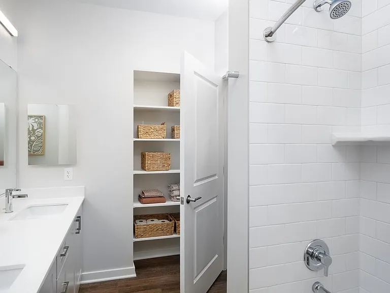 New West Phase - Finish Package III Bathroom with white quartz countertops, grey cabinetry, hard surface flooring, and built in storage closet