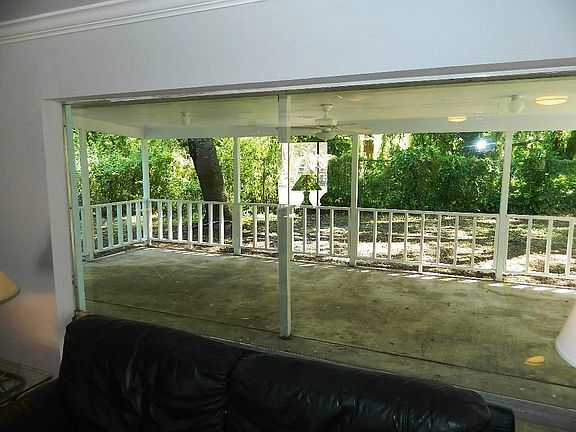 Large plate glass window of the living room offers spectacular view across the entry porch tot he woods beyond.