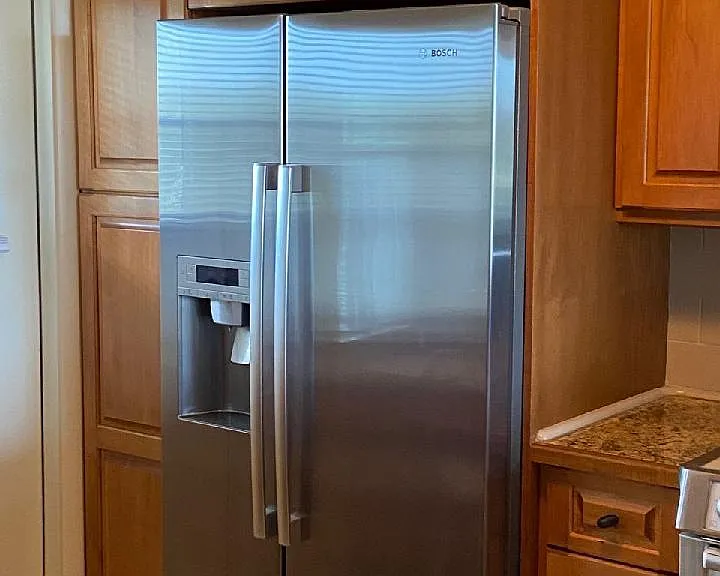 Bosch side-by-side counter-depth refrigerator with filtered water and ice in the door dispenser.
