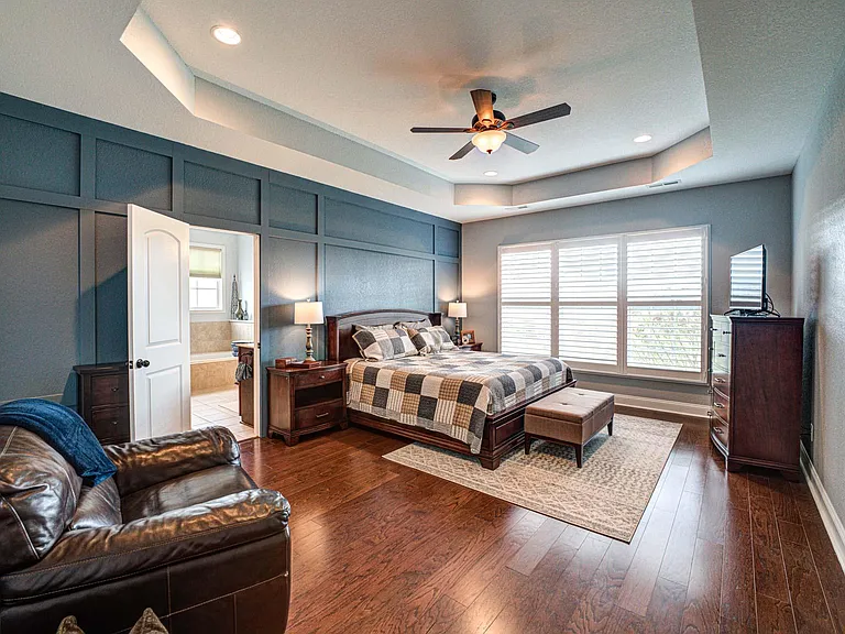 Master bedroom with king bed, dresser, TV and sitting chair.
