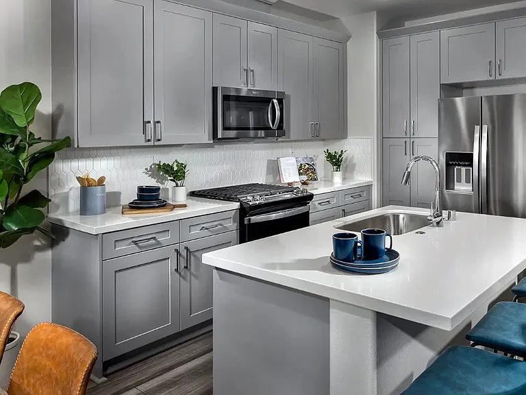 Modern kitchen with quartz countertops, refrigerator, stove/oven, microwave, dishwasher, and bar stools