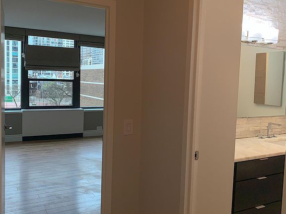 Bedroom and bathroom hallway. Bedroom blinds are blackout and open from both top and bottom.