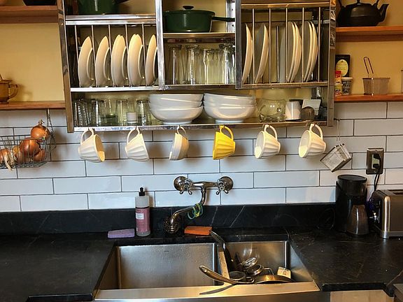 Stainless kitchen sink and open shelves with subway tile.