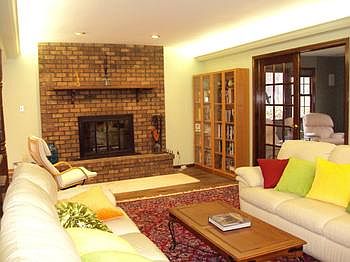 The living room has this brick fireplace and is open to the kitchen. There are french doors leading to the main floor family room.
