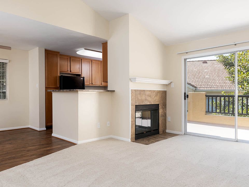 Carpeted Living Room with Wood-burning Fireplace and Balcony