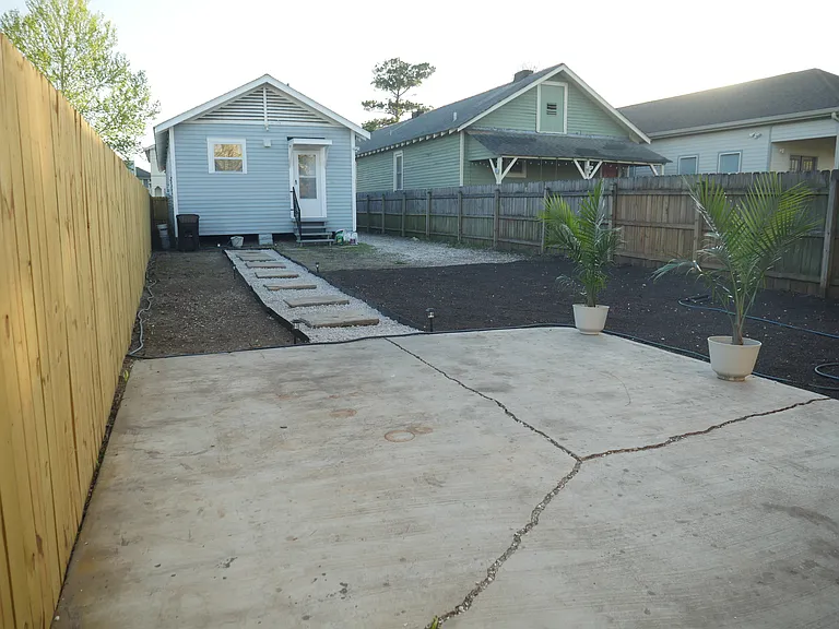 Large private backyard featuring a paver walkway, landscaping rock, and defined outdoor spaces
