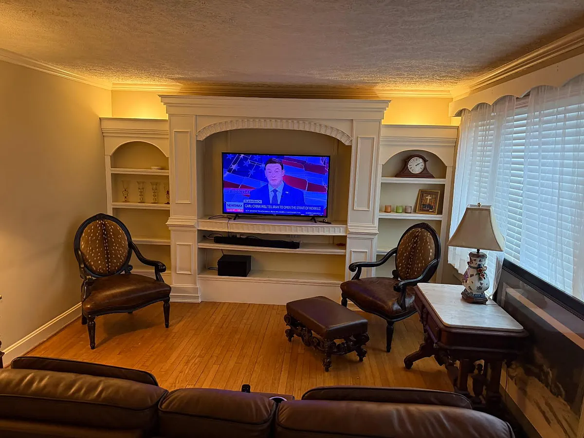 Photo 2 of 6 - Castle Heights Ave - Lebanon, TN Living room features hardwood floors and a built-in entertainment center with shelving, plus seating and side tables. - Castle Heights Ave