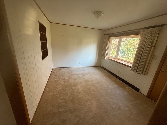 Main floor den with built in bookshelf and bay window view to back yard woods.
