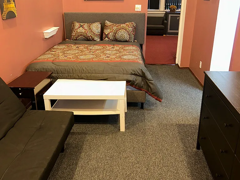 Furnished sleeping area with a full bed, dresser, nightstand, and seating, plus quick access to an adjacent lounge.