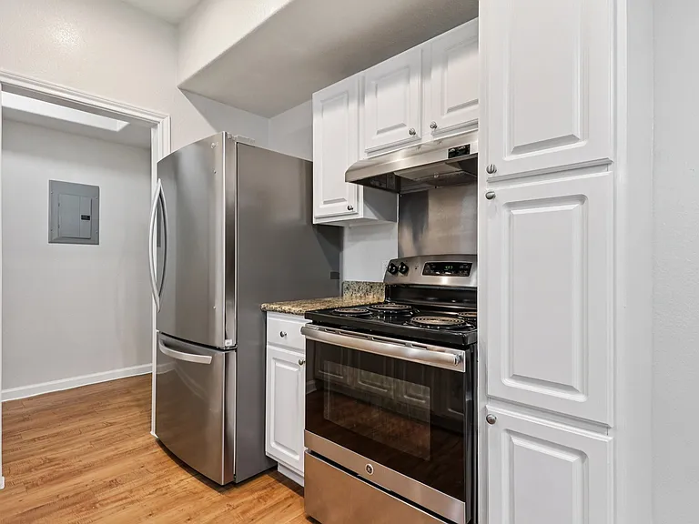 Modern kitchen with sleek stainless steel appliances, elegant white cabinetry, and warm wood-style flooring. Modern kitchen with sleek stainless steel appliances, elegant white cabinetry, and warm wood-style flooring.