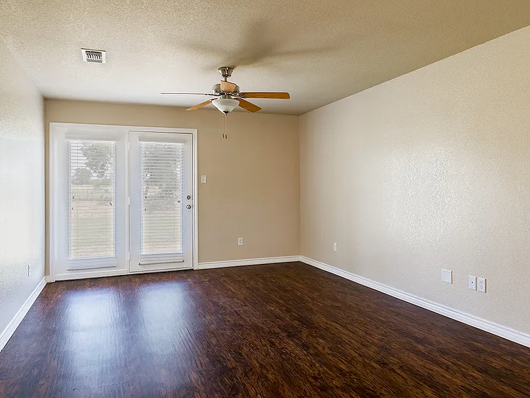 The living room in a Phase 2 apartment home features glass doors leading to the back porch