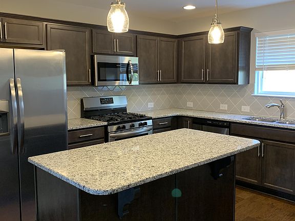 kitchen has granite countertops with an island and tile backsplash