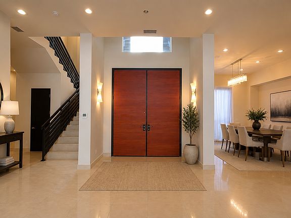 Grand two-story foyer with custom double doors and elegant formal dining room.