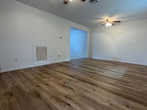 Vista desde la entrada: sala luminosa con piso estilo madera, ventiladores y espacio ideal para reuniones.//

Bright and airy living room view from the front entrance_features wood-look flooring, ceiling fans, and a spacious layout for entertaining.