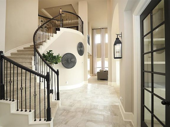 You'll be instantly greeted by a beautifully detailed front door, stunning second floor balcony overlooking the living room and entryway with custom iron railing details, soaring high ceilings, and tile flooring throughout!