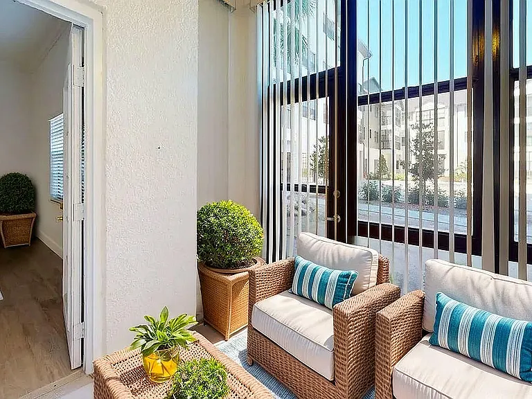 Inviting sunroom with cozy wicker chairs, vibrant green plants, and large windows offering ample natural light.