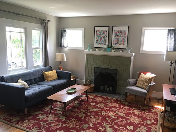 Living room with stone fireplace and large picture window.