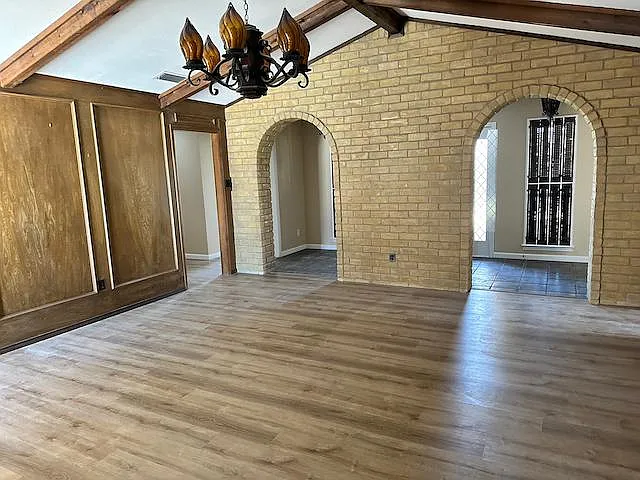 Custom wood paneled and brick living room features ample natural light via windows and skylight. Propane fueled gas fireplace, Spanish light fixtures, built in desk and wet bar found in this spacious room.