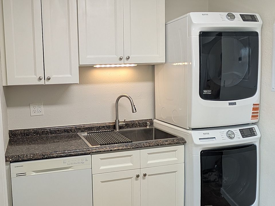 Kitchen cabinets showing dishwasher, stainless steel single bowl sink and brand new washer & dryer.