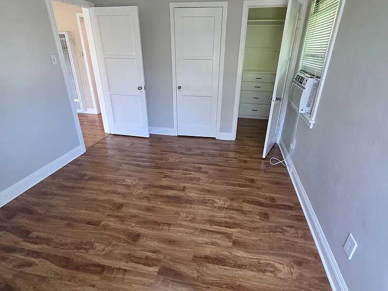 Bedroom with two closets and window air conditioner.