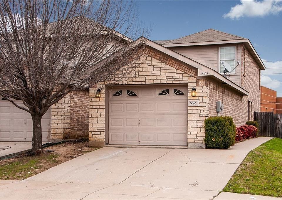 View of front facade featuring stone siding, driveway, and a garage