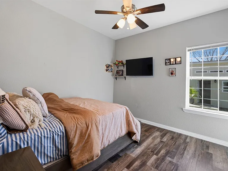 Room featuring wood-finish flooring, a ceiling fan with integrated lighting, and a single-pane window with white trim