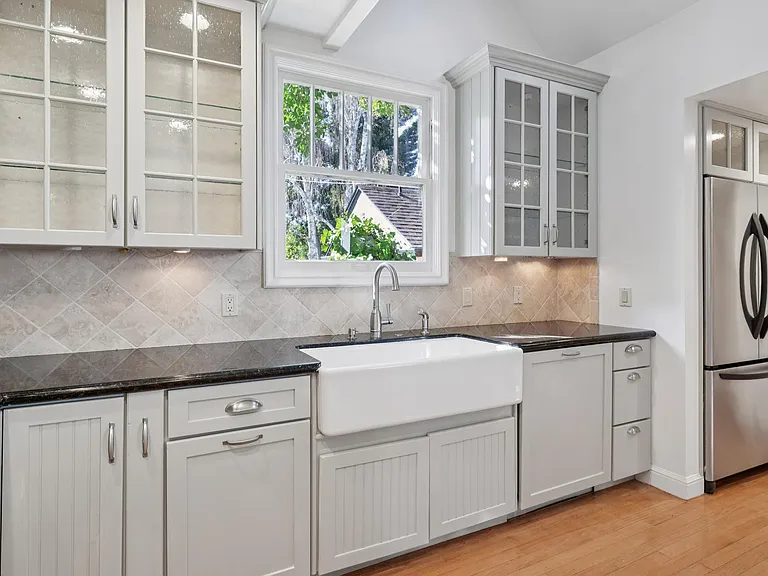 Farmhouse sink with a view of trees.