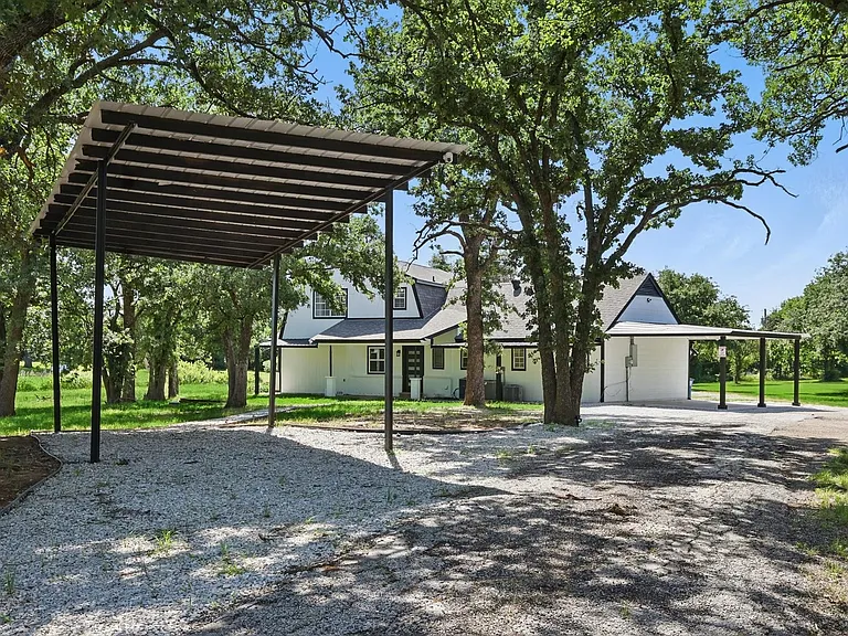 View of front of house with gravel driveway and a carport
