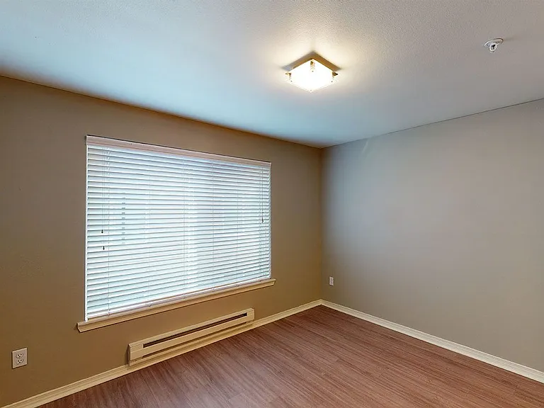Spacious apartment bedroom with wood-style flooring.