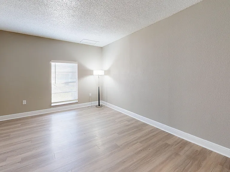 Bright, spacious room with modern wood flooring and a large window letting in natural light, ideal for creating a welcoming living space.