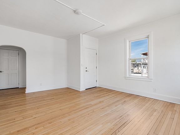 Large living room featuring arched walkways, and light hardwood flooring