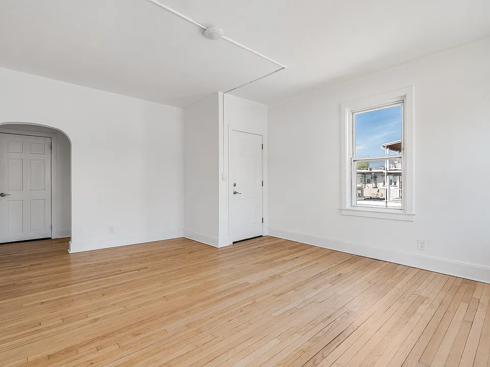 Large living room featuring arched walkways, and light hardwood flooring
