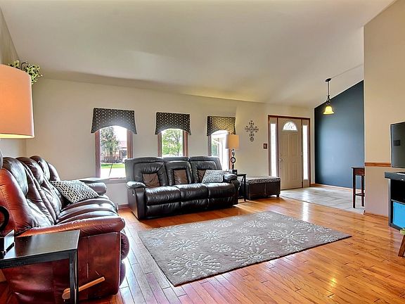 LIVING ROOM OFF THE FOYER FEATURES HARDWOOD FLOORS AND VOLUME CEILING