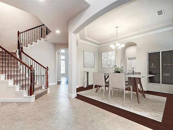 The dining room opens up from the entryway through a majestic archway. Notice the gleaming hardwood flooring, recessed tray ceiling and crown molding. This is an artists impression of just how chic you can make this formal dining room look. The archw