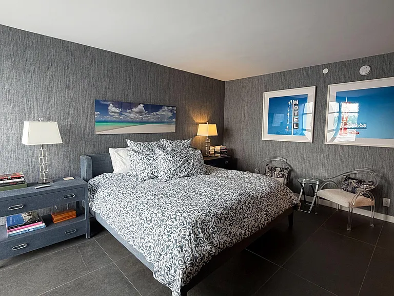 Well-appointed bedroom with a queen bed, nightstands and lamps, plus a sitting area and durable tile flooring.