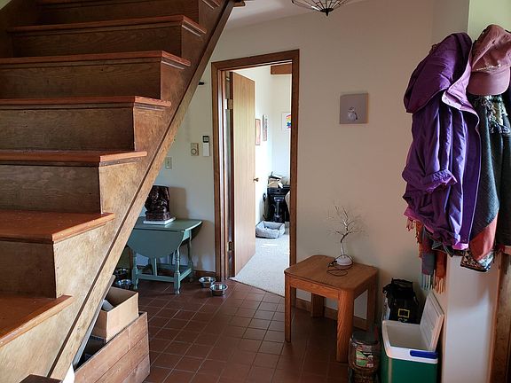 Entryway, ground level. There is no basement. Laundry room is around stairs to the left. Custom wood and kindling box under stairs.