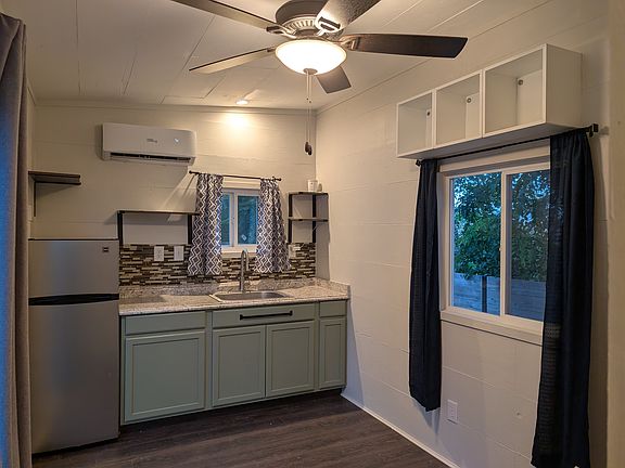 Kitchen with full refrigerator, hot plate, large sink, ceramic tile backsplash, and lots of cabinet and shelf space. Mini split provides heating and cooling. Kitchen / living area ceiling fan to keep air flowing throughout the home.