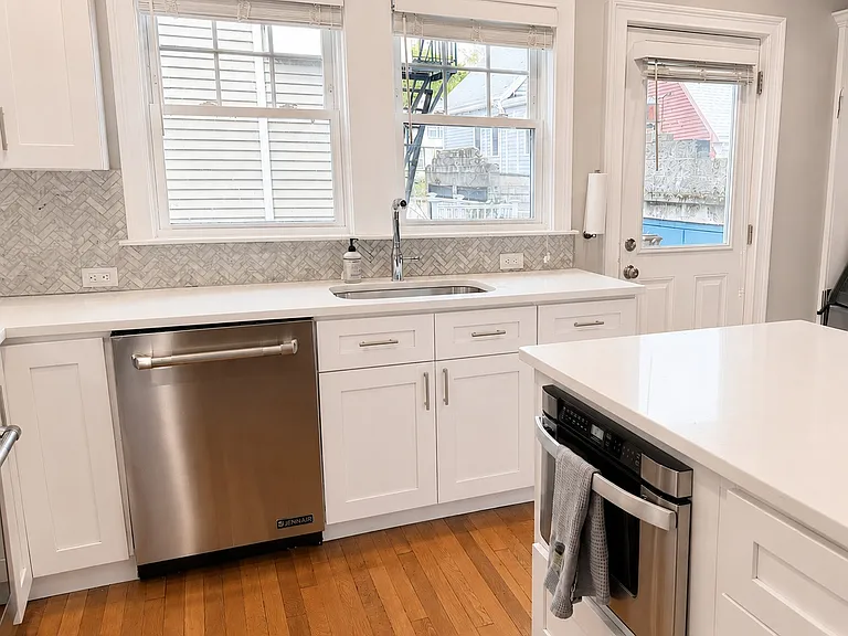 Bright kitchen with large windows, modern backsplash, ample cabinetry and built-in microwave
