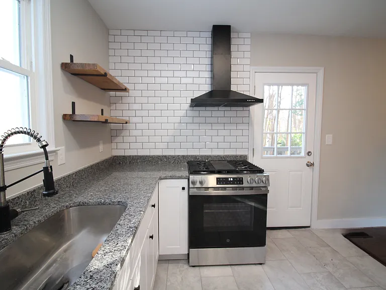Kitchen with quartz counters, gas range, tile backsplash